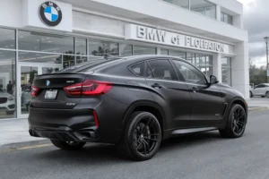 BMW X6 Dark Edition preto fosco, rodas escuras, em frente a concessionária.