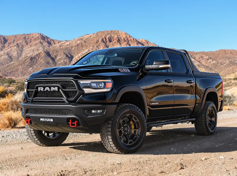 Picape Ram Dakota 2026 preta em trilha de terra com paisagem montanhosa.