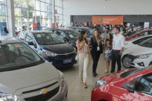 IPI Zero impulsiona vendas de carros em julho: confira os modelos mais vendidos Pessoas em uma concessionária; carros populares como Onix e HB20 com adesivos de 'IPI Zero'.